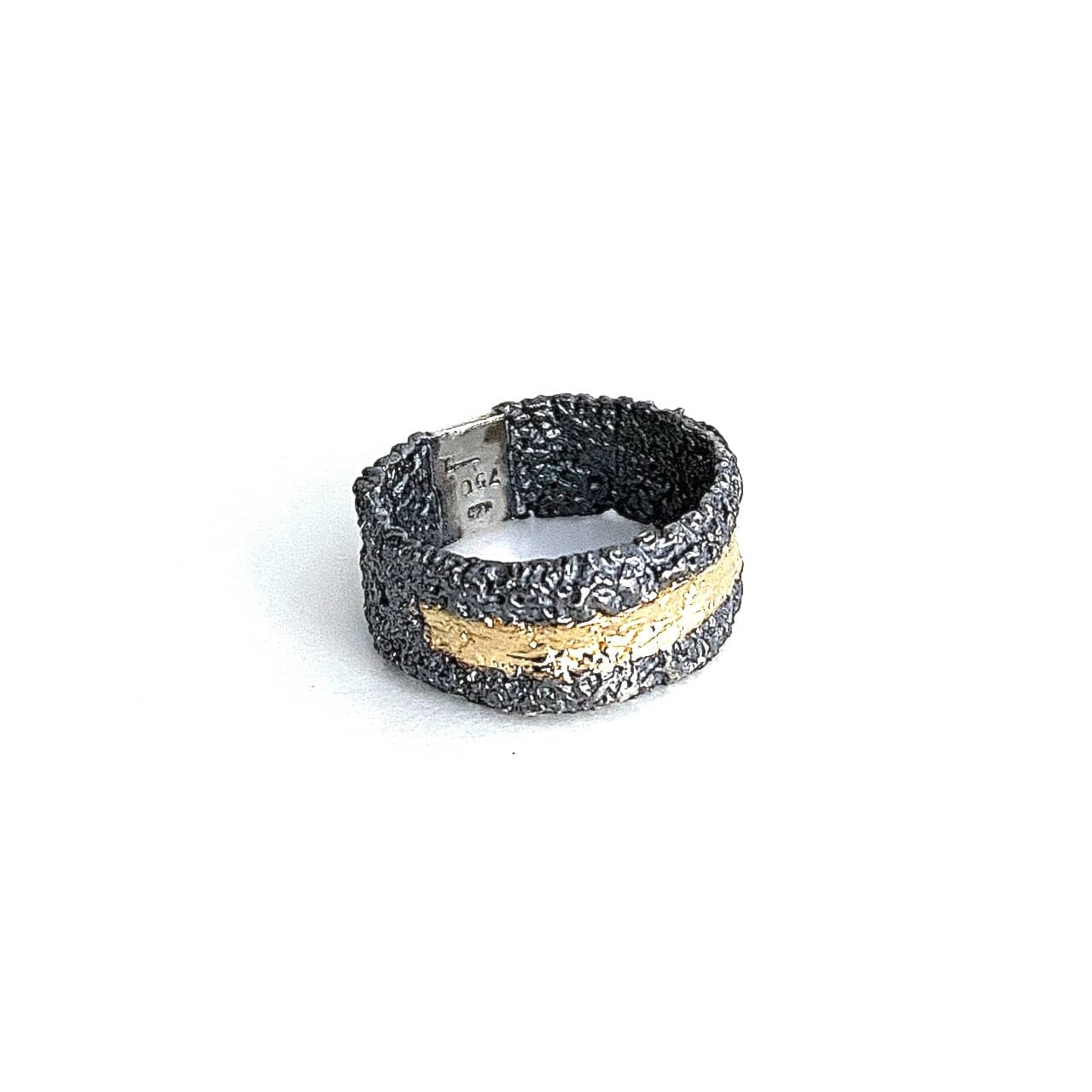 Anneau large en argent patiné noir. et texturé. Sur le dessus un bande d'or jaune est appliquée sur la moitié du bijou.