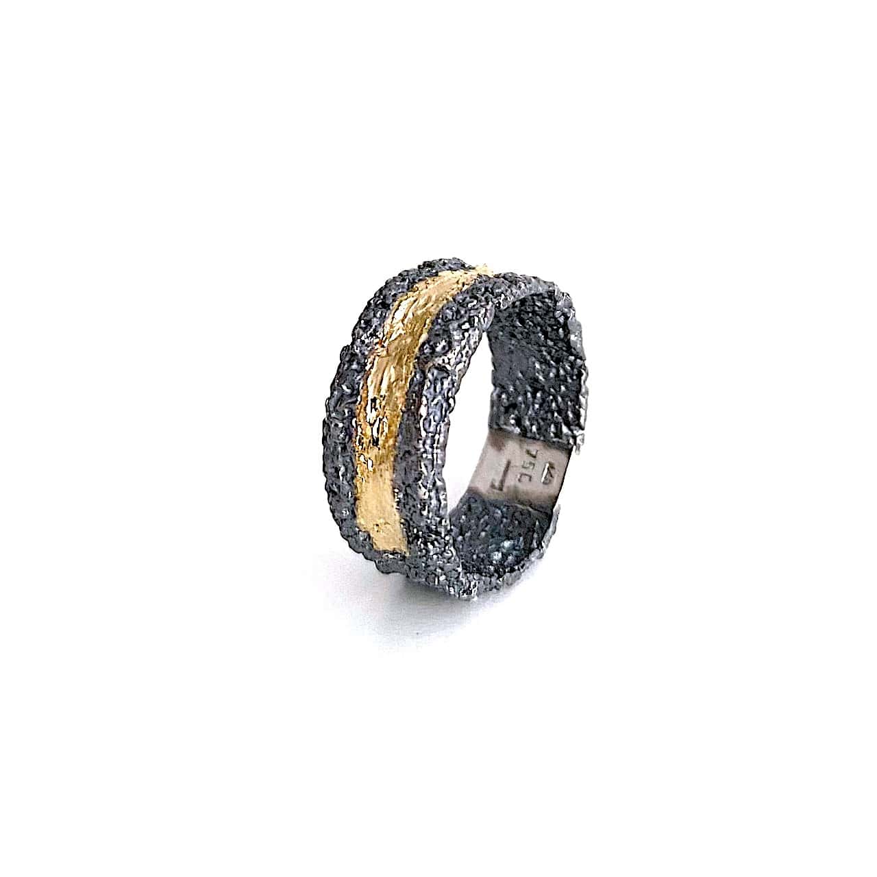 Anneau large en argent texturé et patiné noir. Sur le dessus un bande d'or jaune est appliquée sur la moitié du bijou.