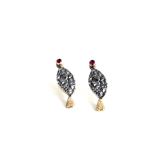 Boucles d'oreilles en forme de petit poisson stylisé. La tête est ornée d'un rubis serti sur le lobe, le corps en argent patiné et texturé, la queue se pare d'or jaune.