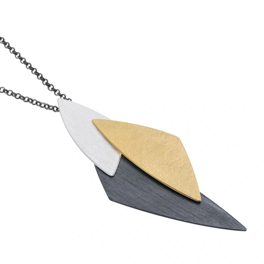 Ce pendentif géométrique articulé est composé de trois triangles de tailles et  finitions variées:  l'argent brossé, oxydé et plaqué or jaune. Il est monté sur une chaîne patinée noire.