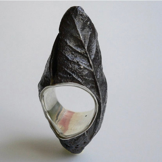 Bague haute en fer rouillé et patiné, née de moulages de feuilles d'arbres. Elle composée d'un anneau large en argent en force de douille offrant ainsi un confort et son maintien.