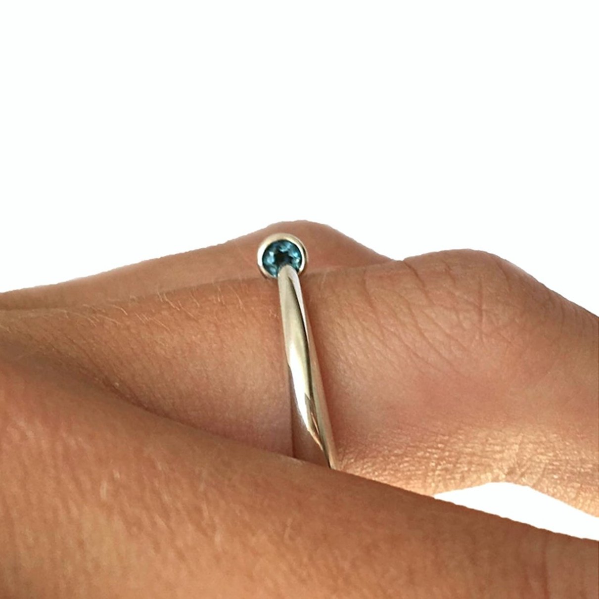 Bague effilée en argent poli se caractérise par un anneau arrondi confortable qui se rétrécit en pointe sur une topaze bleue.