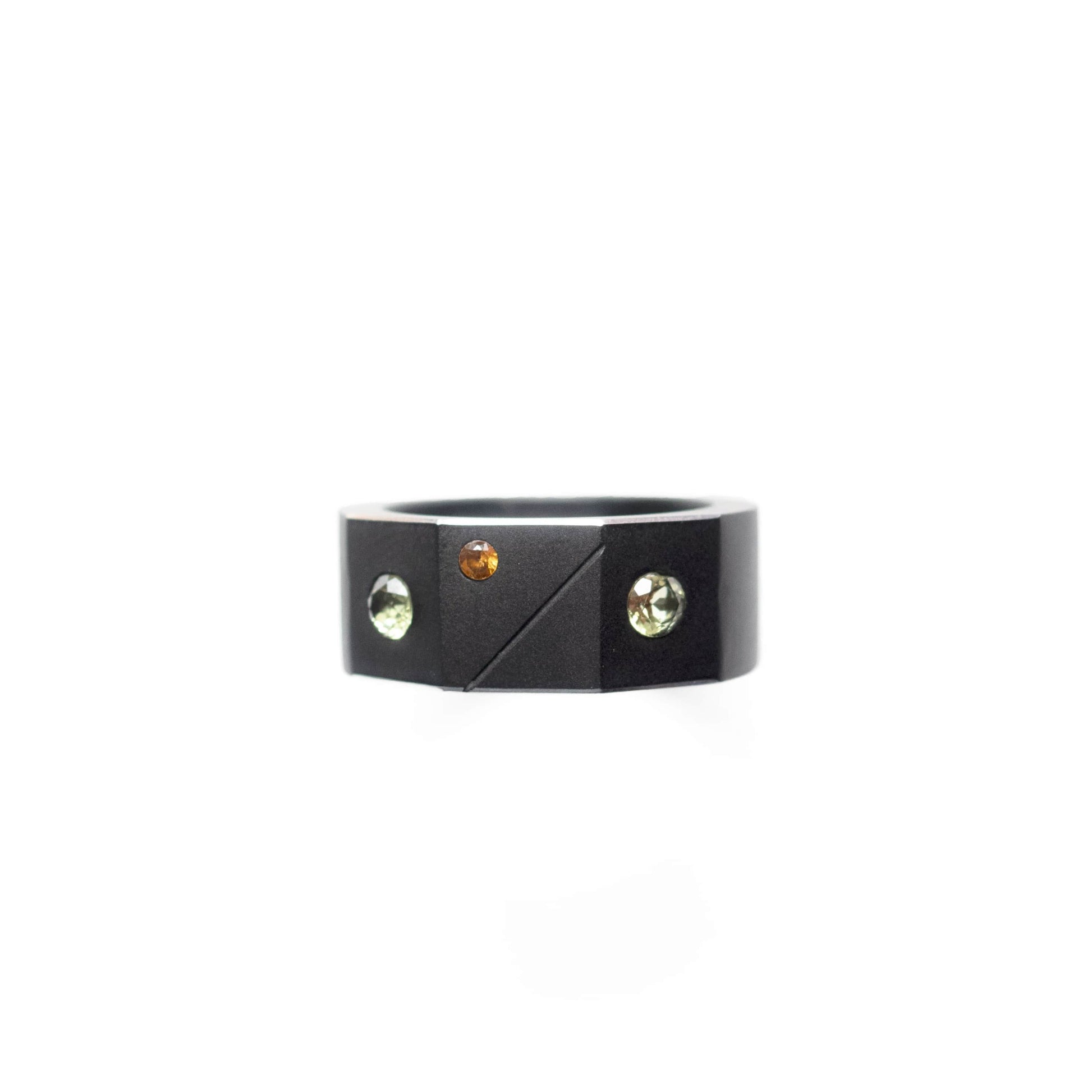 Bague forme chevalière en aluminium anodisé noir orné de deux péridots et d'un grenat hessonite.