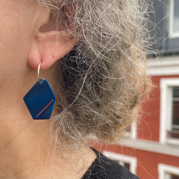 Boucle d'oreille géométrique en titane bleu montée sur tige d'argent en forme de créole. Boucle portée détail oreille de profil.