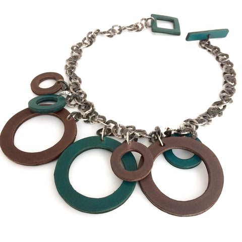 Sept cercles de cuir gris et vert de différents tailles présentés sur chaîne acier aux anneaux martelés.