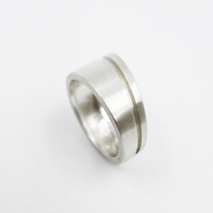 Bague pour homme et femme en argent brossé. Un fin liseré creusé dans le métal confirme l'asymétrie et la sobriété du design