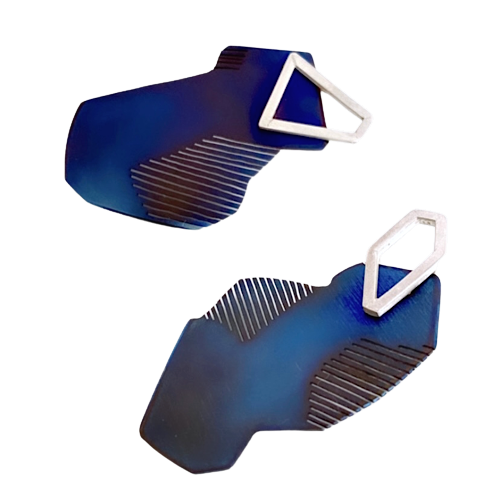 Boucles d'oreilles asymétriques en titane bleu avec découpes en forme de stries sur les côtés. sur le dessus est fixée une pièce géometrique en argent 