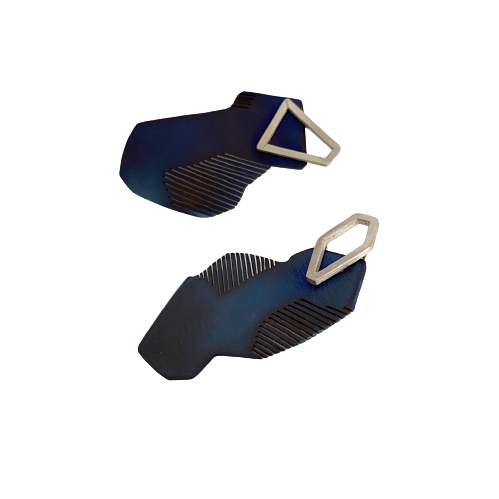 Boucles d'oreilles asymétriques en titane bleu avec découpes en forme de stries sur les côtés. sur le dessus est fixée une pièce géometrique en argent 