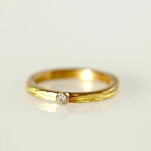 Bague ciselée en or jaune 18 carats ornée d'un petit diamant blanc.