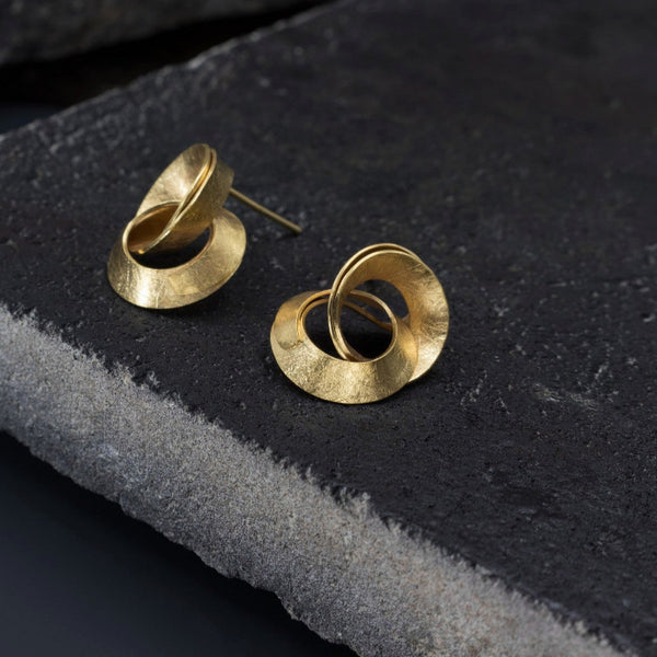 Clous d'oreilles représentant deux anneaux entrelacés en argent plaqué or jaune posés sur décor noir