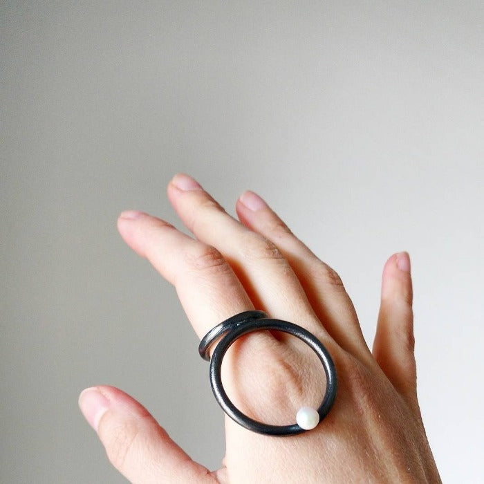 Bague composé d'un grand cercle en argent patiné noir orné d'une perle blanche.