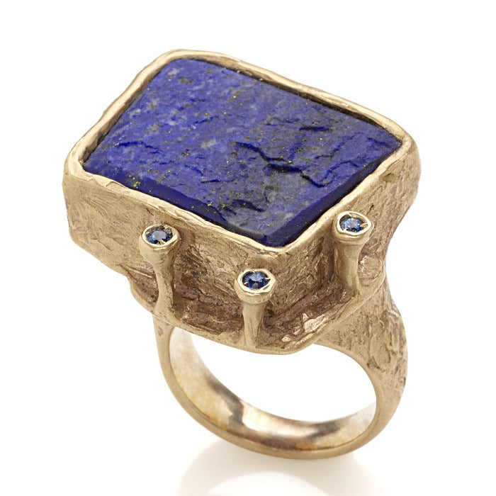 Bague sculpturale en bronze ornée d'un lapis-lazuli brut rectangulaire et 3 saphirs bleus sur un angle.