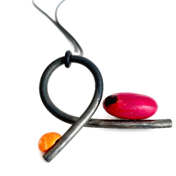 Pendentif en fer forgé paré d'un coquillage escargot orange et d'une graine rose framboise du Mali. presenté sur lien de caoutchouc, pièce unique 2017