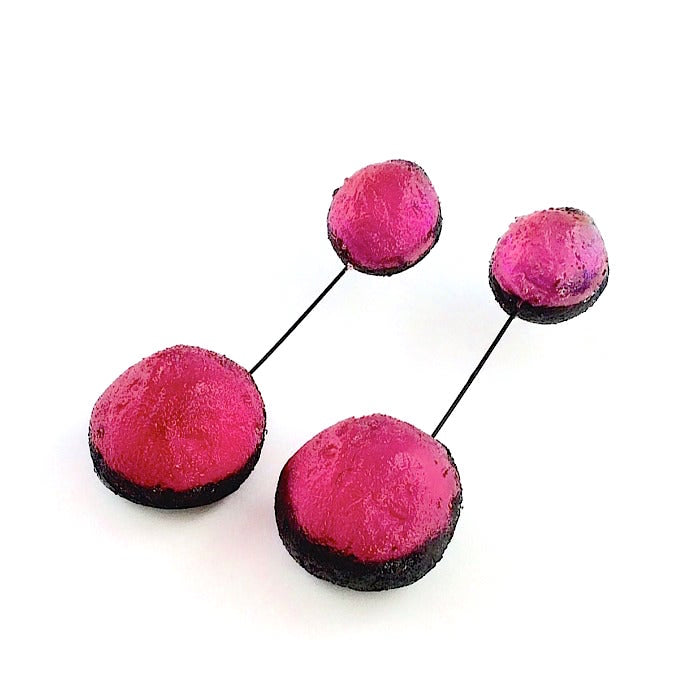 Boucles d'oreilles constituées de 2 sphères en résine irisée fushia, reliées par un cable noir. 