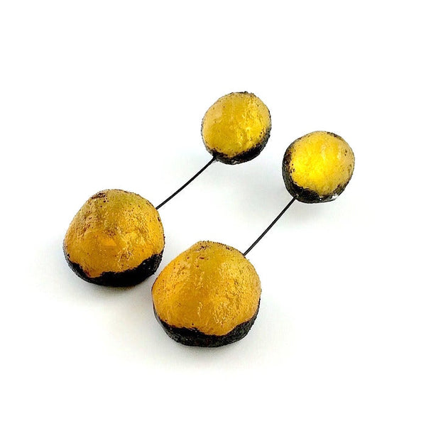 Boucles d'oreilles constituées de 2 sphères en résine irisée jaune d'or, reliées par un cable noir. 