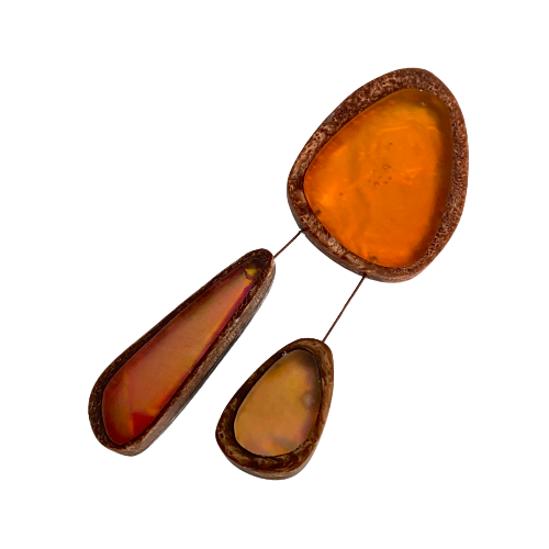Broche en résine orange composée de trois éléments de différentes tailles,deux petits éléments sont reliés au plus grand par un cable rigide noir. fermeture aimant