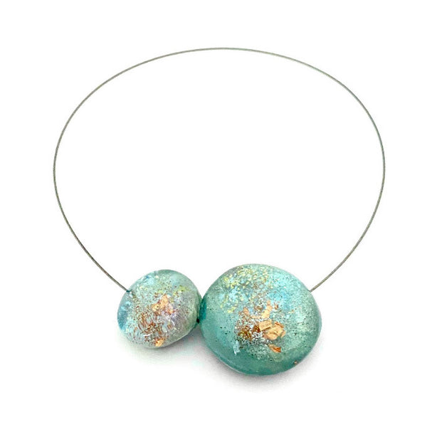 Collier composé de 2 bulles de résine irisée bleu clair, assemblé sur un cable gris.fermoir aimanté