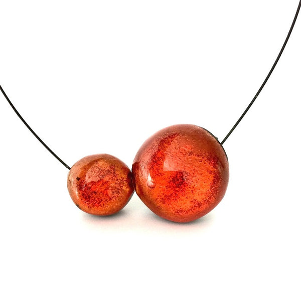 Collier composé de 2 bulles de résine irisée orange, assemblé sur un cable gris.fermoir aimanté
