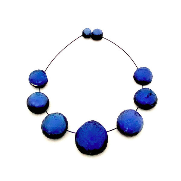 Collier composé de 7 sphères de résine bleu foncé assemblées sur cable noir, fermoir aimanté.