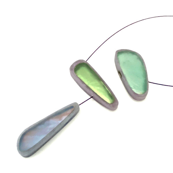 Collier composé de 3 éléments en résine irisée de couleur vert,bleu,gris assemblés sur un cable noir fin et solide.