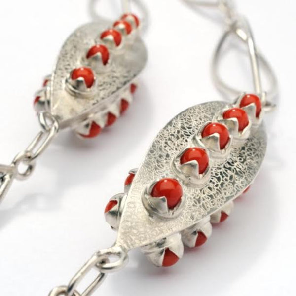 Sautoir argent composé de 15 anneaux de forme ogive et de 2 éléments finement guillochés sertis chacun de 15 perles de corail de Méditerranée.