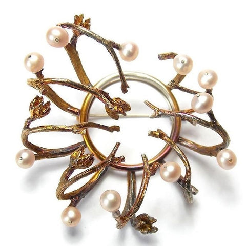 Broche en argent patiné en forme de couronne de brindilles ouvragée de 11 perles d'eau douce rosées. Pièce unique.